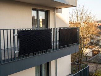 Balkonkraftwerk mit zwei schwarzen Solarmodulen an einem Balkongeländer eines Mehrfamilienhauses