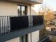Balkonkraftwerk mit zwei schwarzen Solarmodulen an einem Balkongeländer eines Mehrfamilienhauses